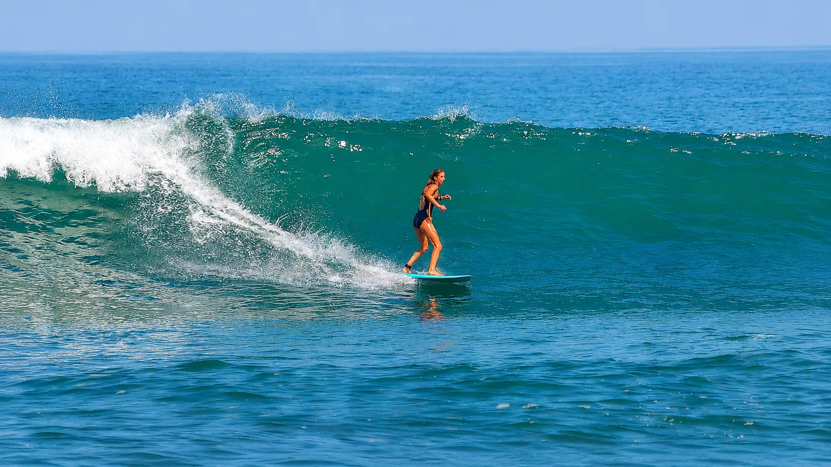 A coach and student paddling out side by side on their soft-top boards, both smiling